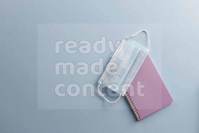 A purple notebook with different school supplies on blue background