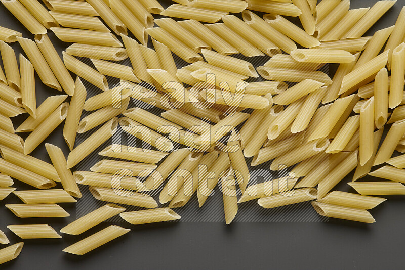 Mini penne pasta on grey background