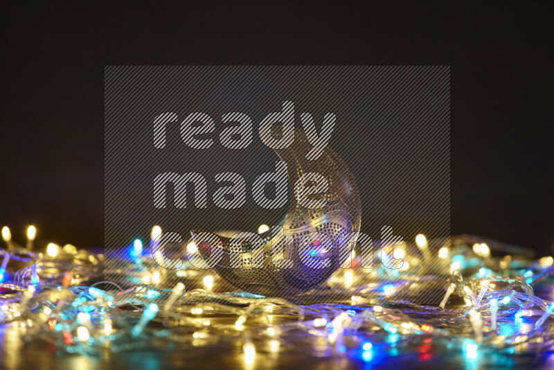 A traditional ramadan lantern surrounded by glowing fairy lights in a dark setup