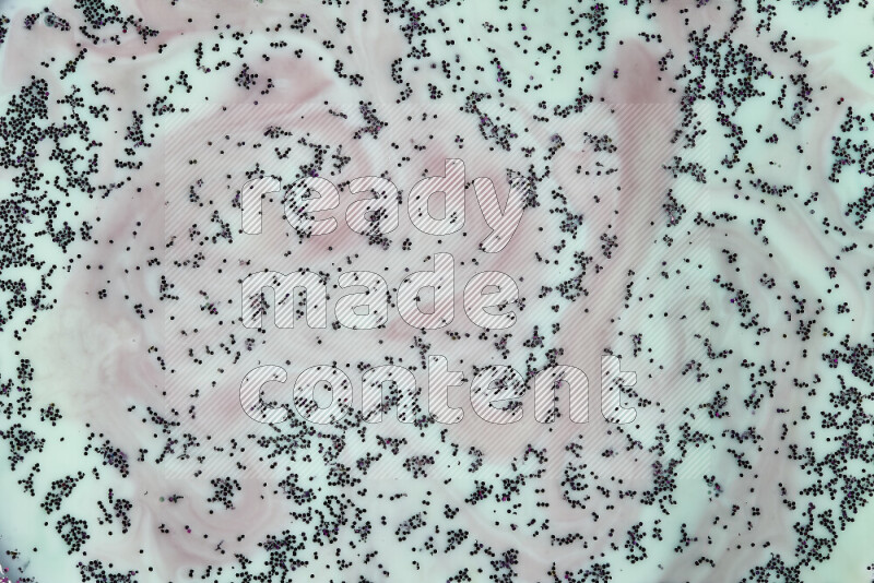 A close-up of swirls of red with sparkling purple glitter scattered on green background