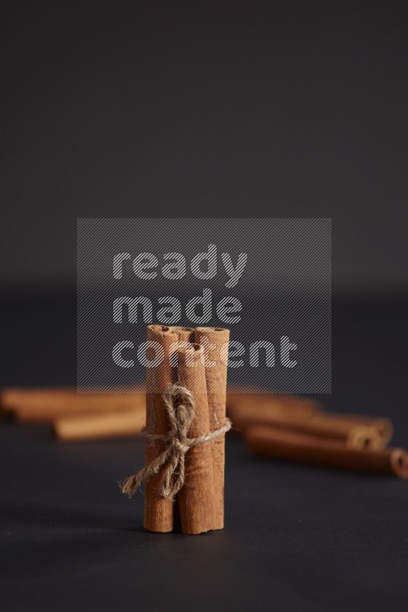 أعواد من القرفة مربوطة مع المزيد من أعواد القرفة علي خلفية سوداء