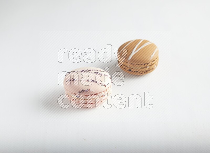45º Shot of of two assorted Brown Irish Cream, and pink orange blossom macarons on white background