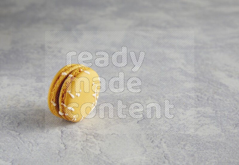 45º Shot of Yellow Piña Colada macaron on white  marble background