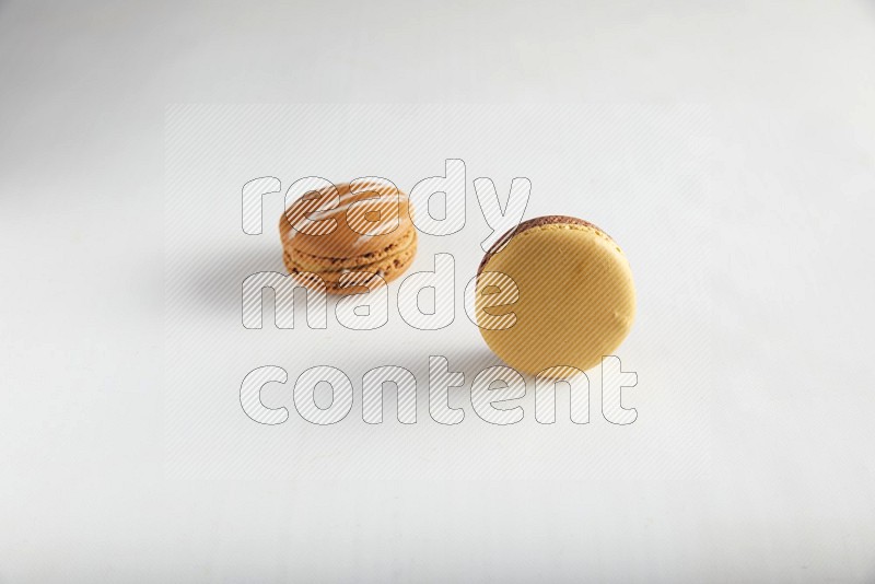 45º Shot of of two assorted Brown Irish Cream, and Yellow, and Brown Chai Latte macarons on white background