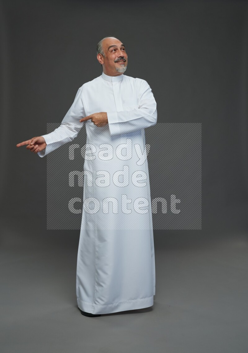 Saudi man without shomag Standing Interacting with the camera on gray background