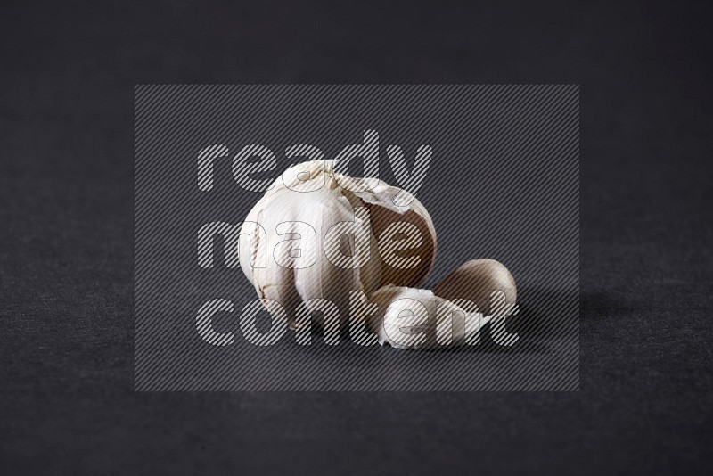 A whole garlic bulb on a black flooring in different angles