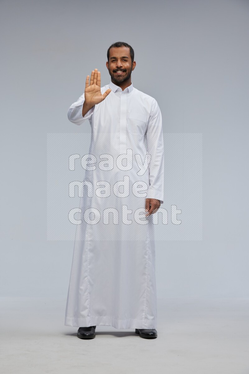 Saudi man Wearing Thob standing interacting with the camera on Gray background