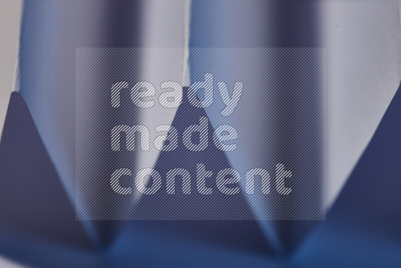 صورة مجردة مقربة تظهر طيات ورقية هندسية حادة بتدرجات اللون الأزرق