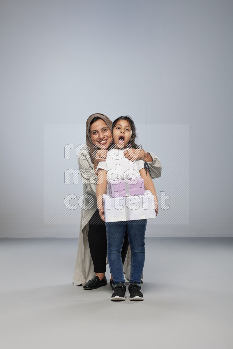 A girl giving a gift to her mother on gray background