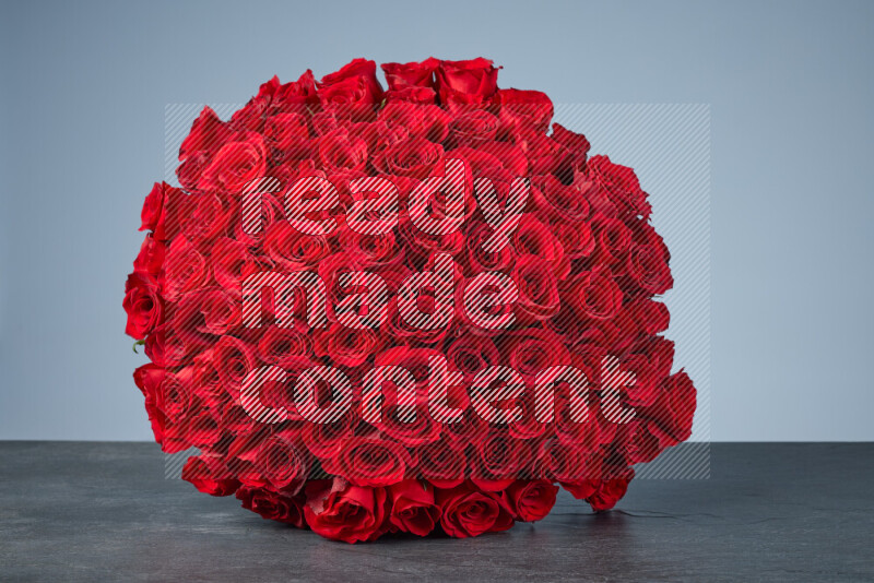 A sphere of vibrant red roses arranged tightly on black marble background
