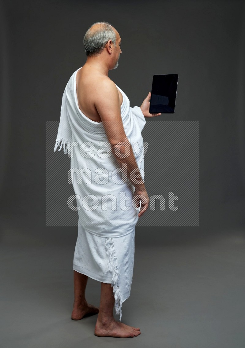 A man wearing Ehram Standing working on tablet on gray background