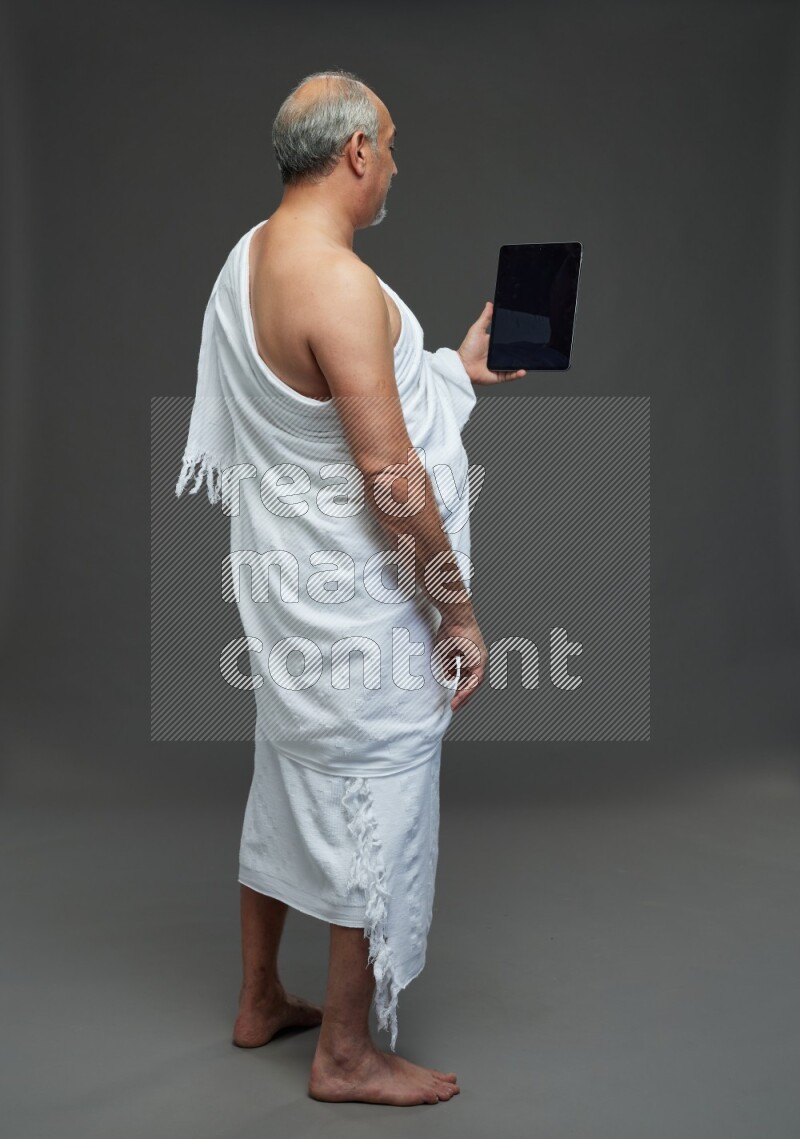 A man wearing Ehram Standing working on tablet on gray background