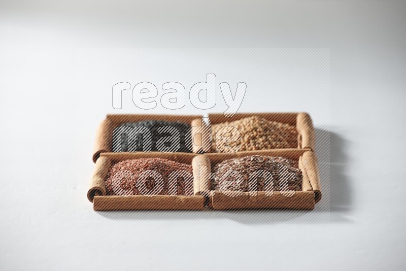 4 squares of cinnamon sticks full of black seeds, mustard seeds, flaxseeds and garden cress on white flooring