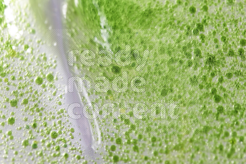 لقطات مقربة لقطرات ألوان مائية خضراء على سطح الزيت على خلفية بيضاء