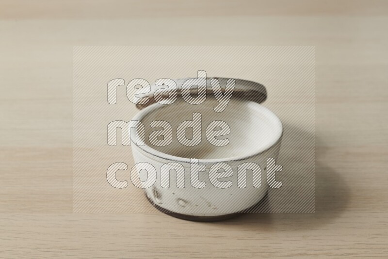 A white pottery bowl on light wooden background