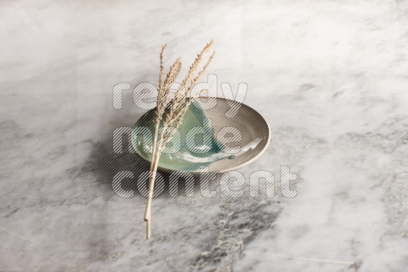 Wheat stalks on multicolored pottery plate on grey marble background
