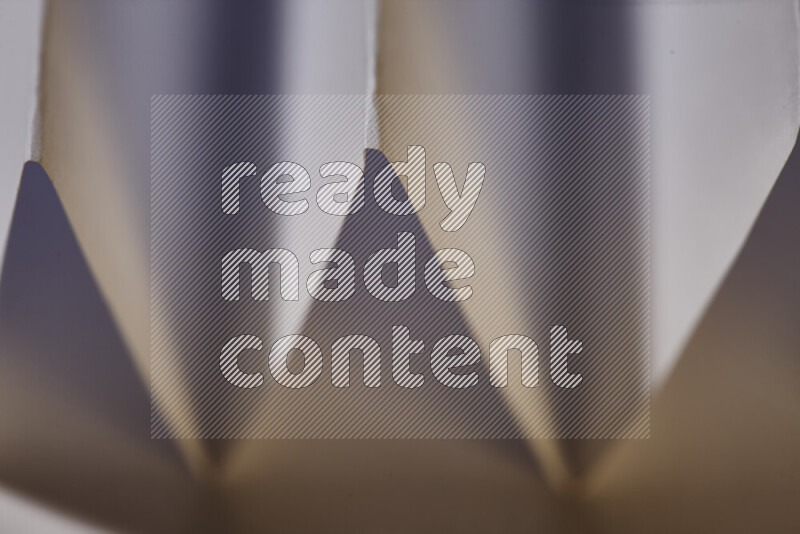 صورة مجردة مقربة تظهر طيات ورقية هندسية حادة بتدرجات اللون الأبيض مع درجات لونية دافئة