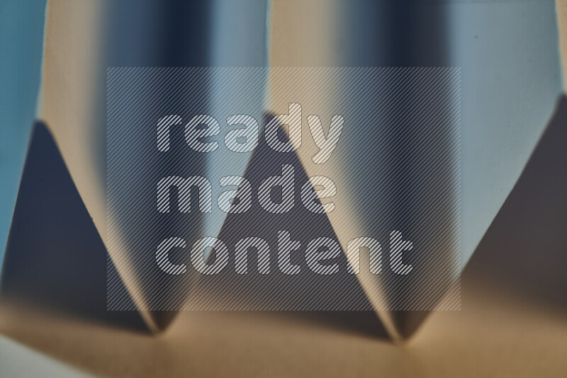 A close-up abstract image showing sharp geometric paper folds in blue gradients and warm tones