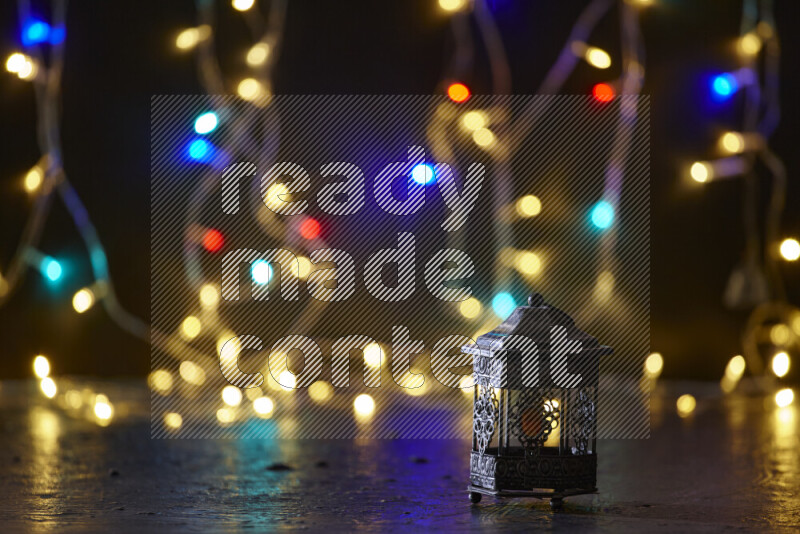 A traditional ramadan lantern surrounded by glowing fairy lights in a dark setup