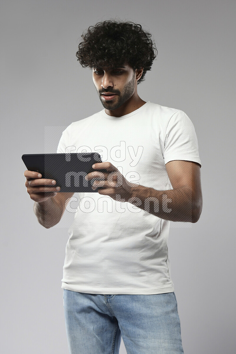 رجل يرتدي ملابس كاجوال يلعب علي تابلت علي خلفية بيضاء
