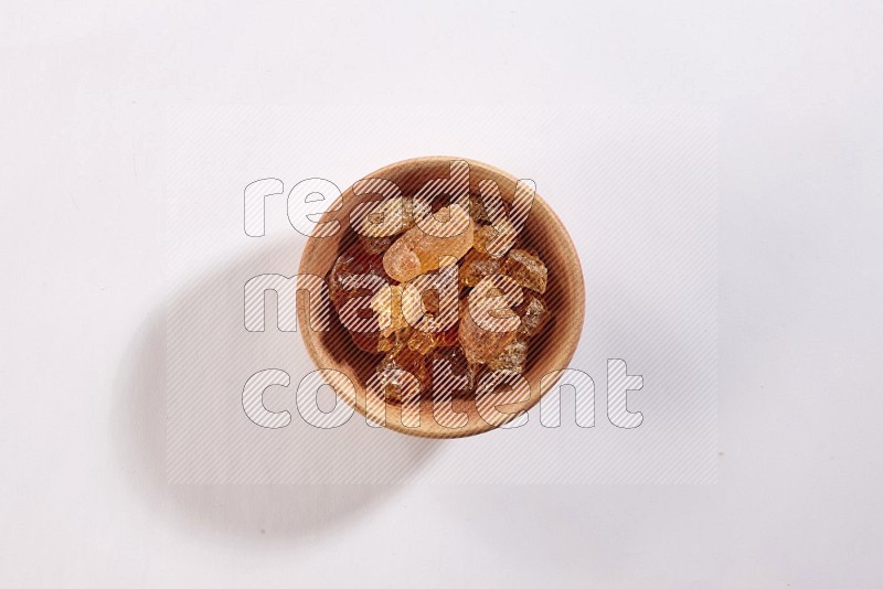 A wooden bowl full of gum arabic on a white flooring