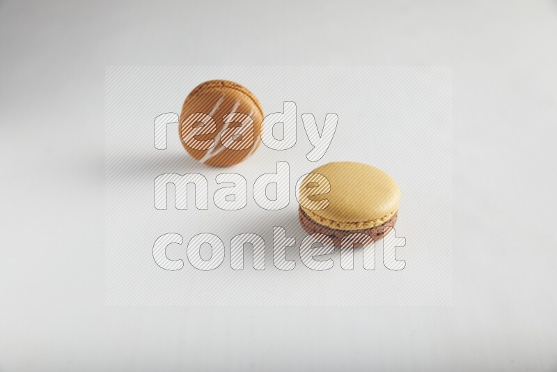 45º Shot of of two assorted Brown Irish Cream, and Yellow, and Brown Chai Latte macarons on white background