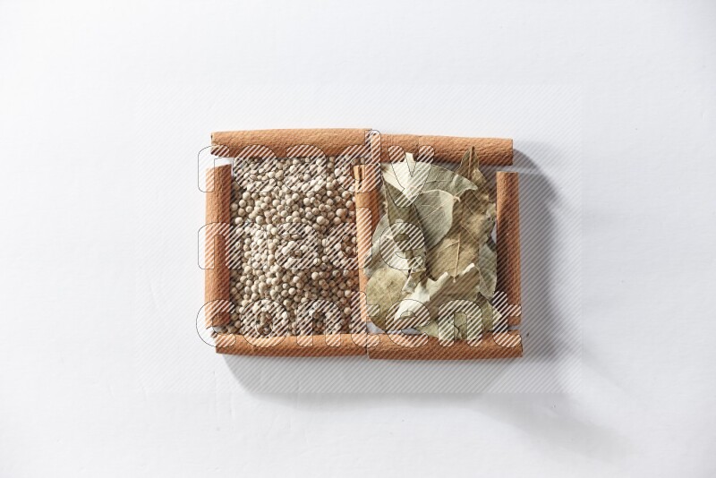 2 squares of cinnamon sticks full of white pepper and bay laurel leaves on white flooring