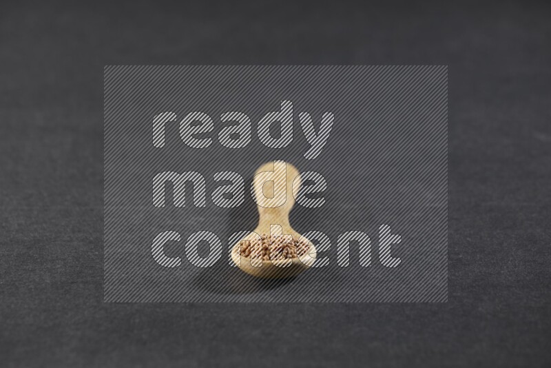 ملعقة خشبية ممتلئة ببذور الخردل علي خلفية سوداء