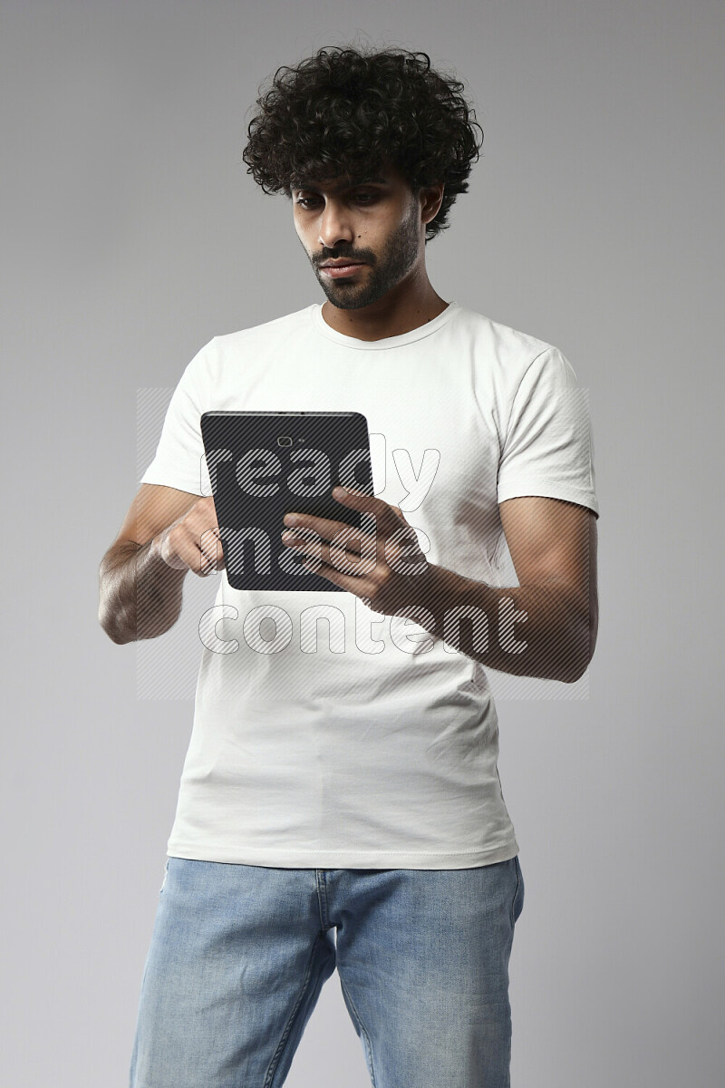 رجل يرتدي ملابس كاجوال يتصفح تابلت علي خلفية بيضاء