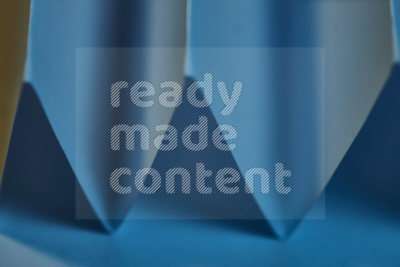 صورة مجردة مقربة تظهر طيات ورقية هندسية حادة بتدرجات اللون الأزرق