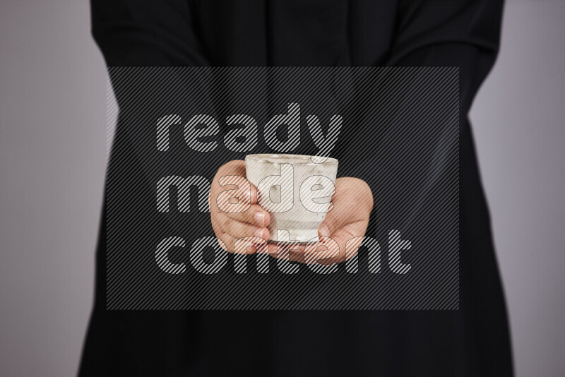 A woman in black abaya holding different pottery essentials in different positions