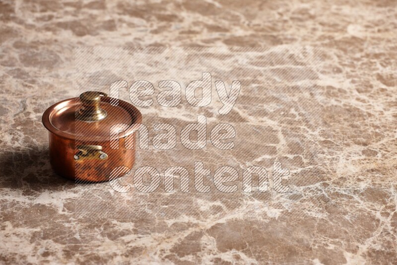 A small copper pot on beige marble background
