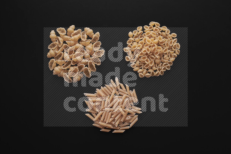 Different pasta types in bunches on black background