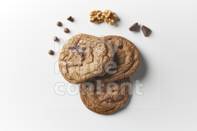 Chocolate chips cookies with chocolate and walnuts beside it on a white background