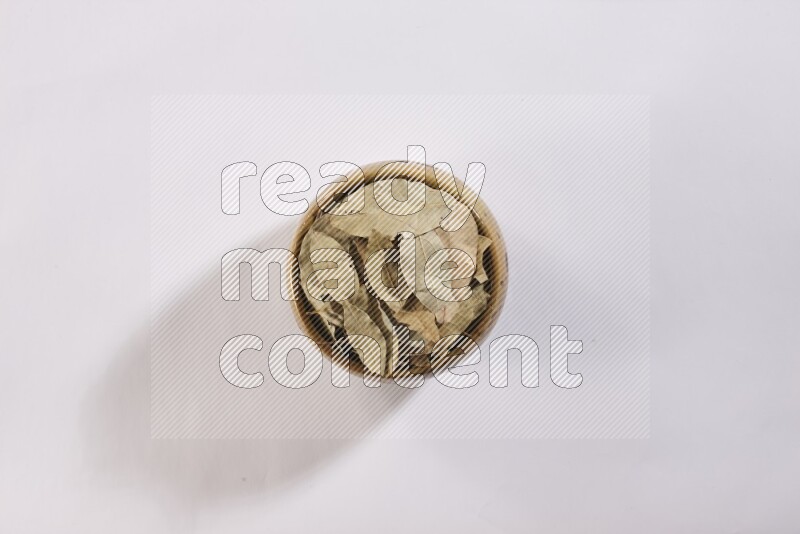 وعاء فخاري متعدد الألوان ممتلئ بأوراق الغار المجففة على أرضية بيضاء