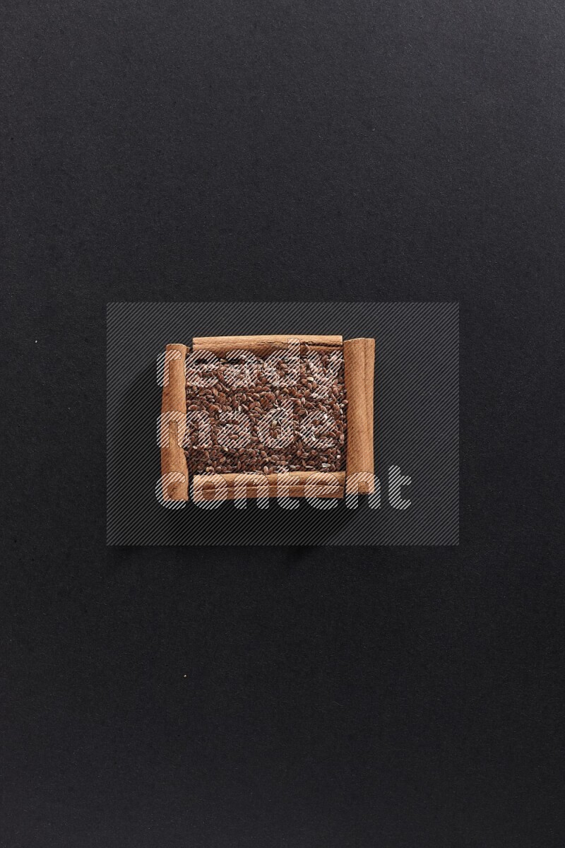 A single square of cinnamon sticks full of flaxseeds on black flooring