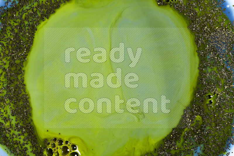 لقطة مقربة لبريق ذهبي متلألئ منتشر على خلفية من اللون الأزرق والأخضر في حركات دائرية