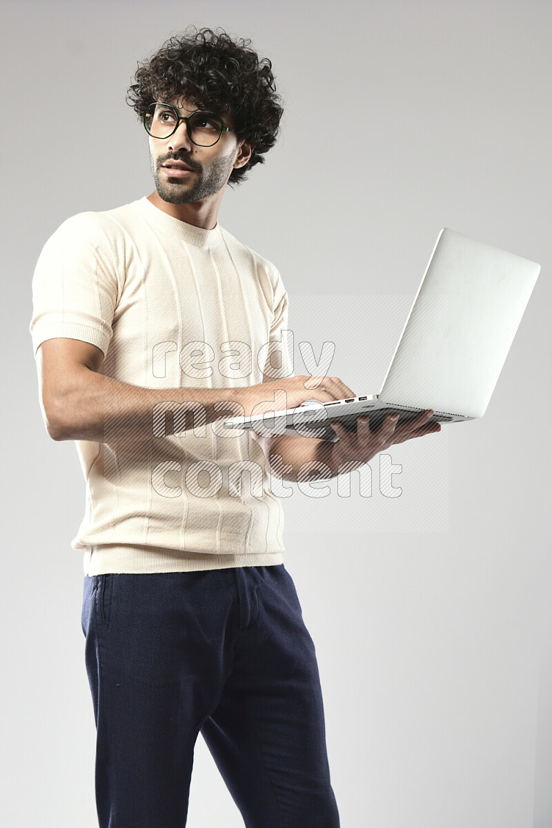 A man wearing casual standing and working on a laptop on white background