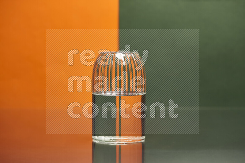 The image features a clear glassware filled with water, set against orange and dark green background