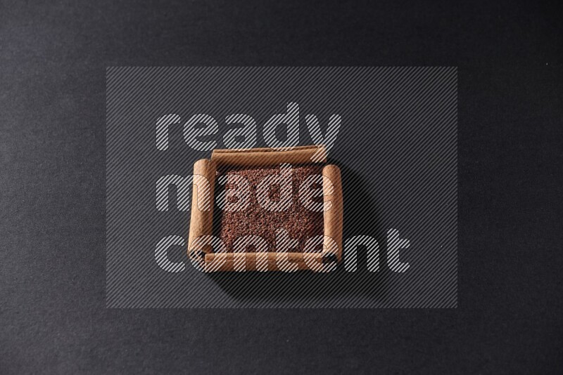 A single square of cinnamon sticks full of garden cress on black flooring