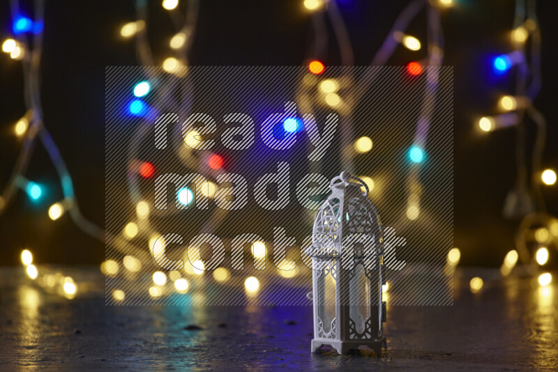 A traditional ramadan lantern surrounded by glowing fairy lights in a dark setup