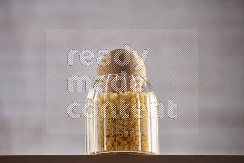 Raw pasta in glass jars on beige background