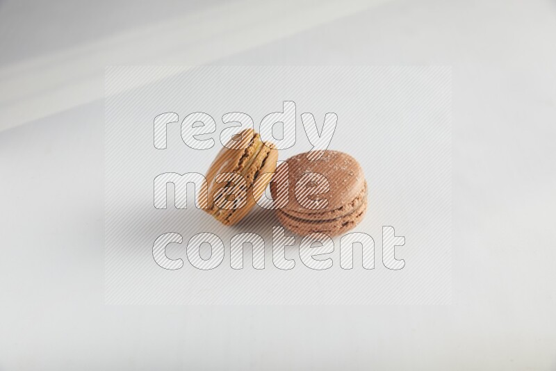 45º Shot of of two assorted Brown Irish Cream, and Brown Hazelnuts macarons on white background