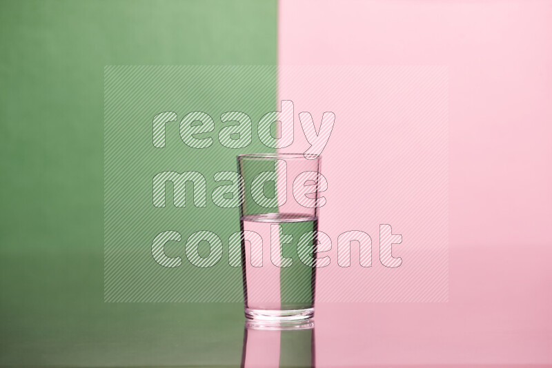 The image features a clear glassware filled with water, set against green and rose background