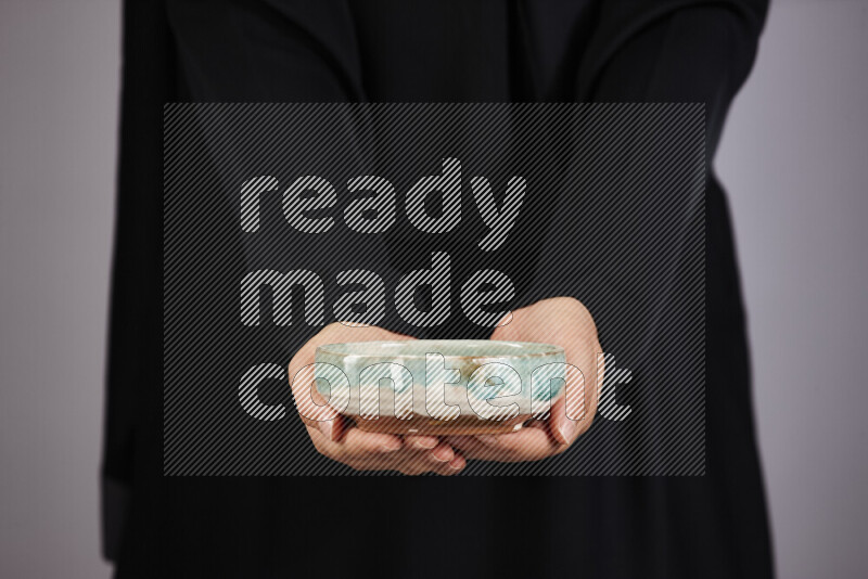 A woman in black abaya holding different pottery essentials in different positions