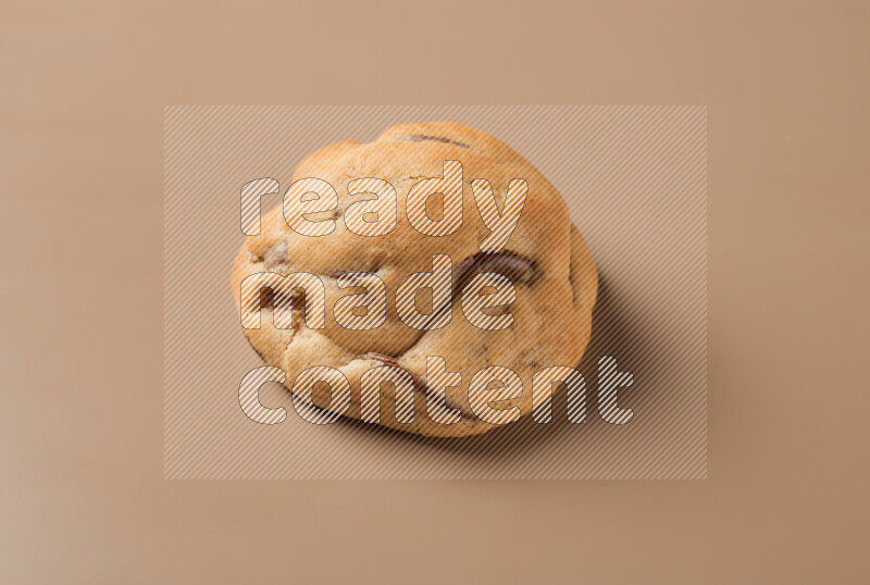 a whole chocolate chip cookie on a brown background