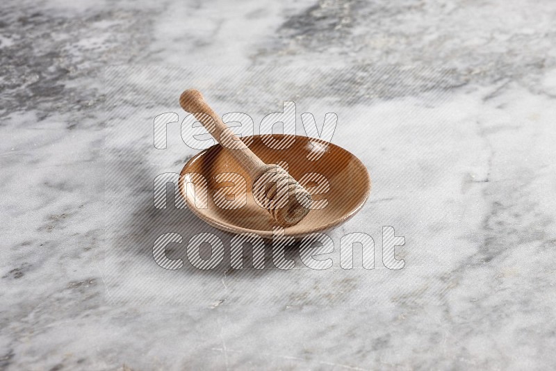 Multicolored Pottery Plate with wooden honey handle in it, on grey marble flooring, 45 degree angle