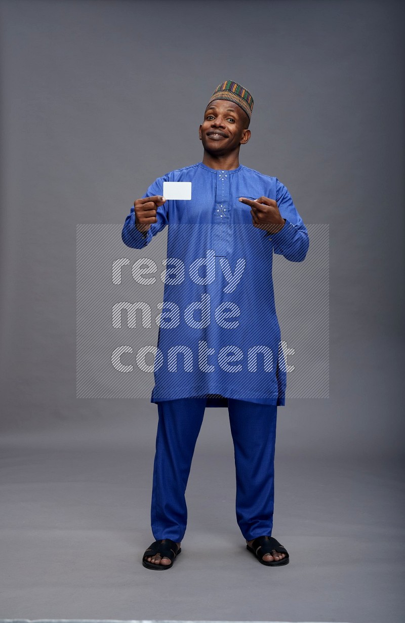 Man wearing Nigerian outfit standing holding ATM card on gray background