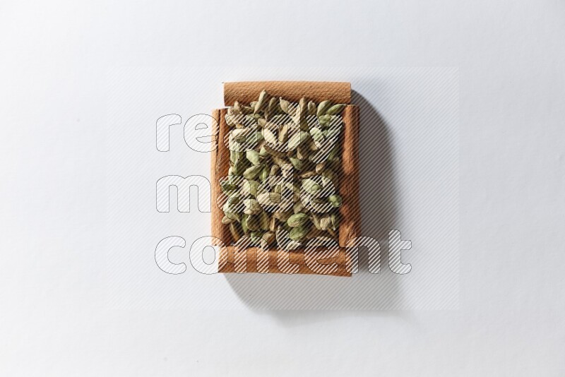 A single square of cinnamon sticks full of cardamom on white flooring