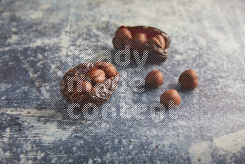 two hazelnuts stuffed madjoul dates on a rustic blue background